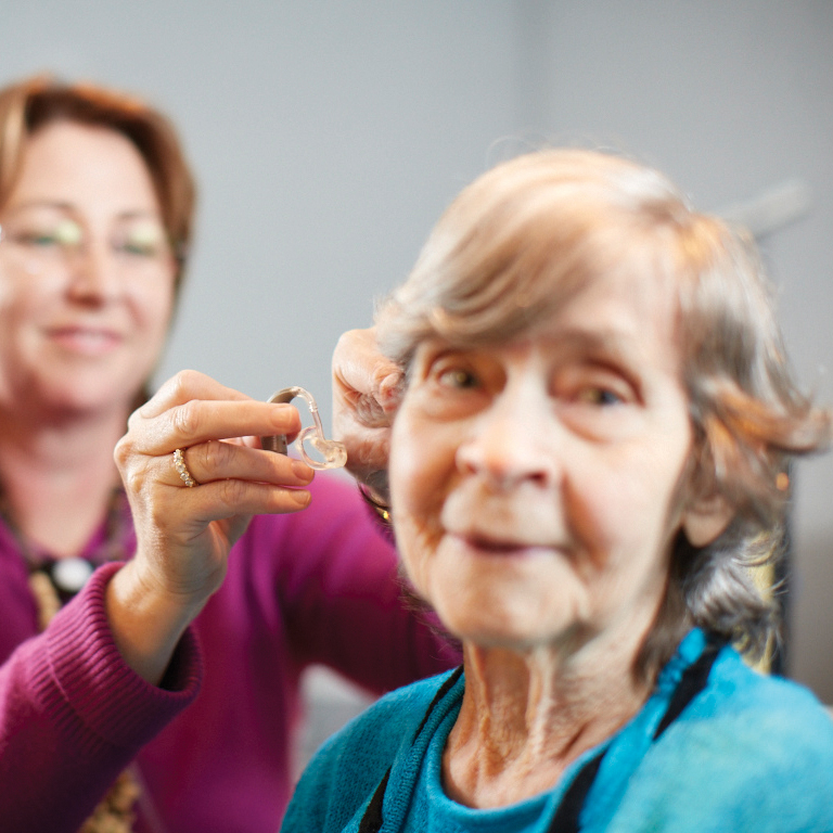 ENT Specialist fitting a hearing aid on an elderly patient